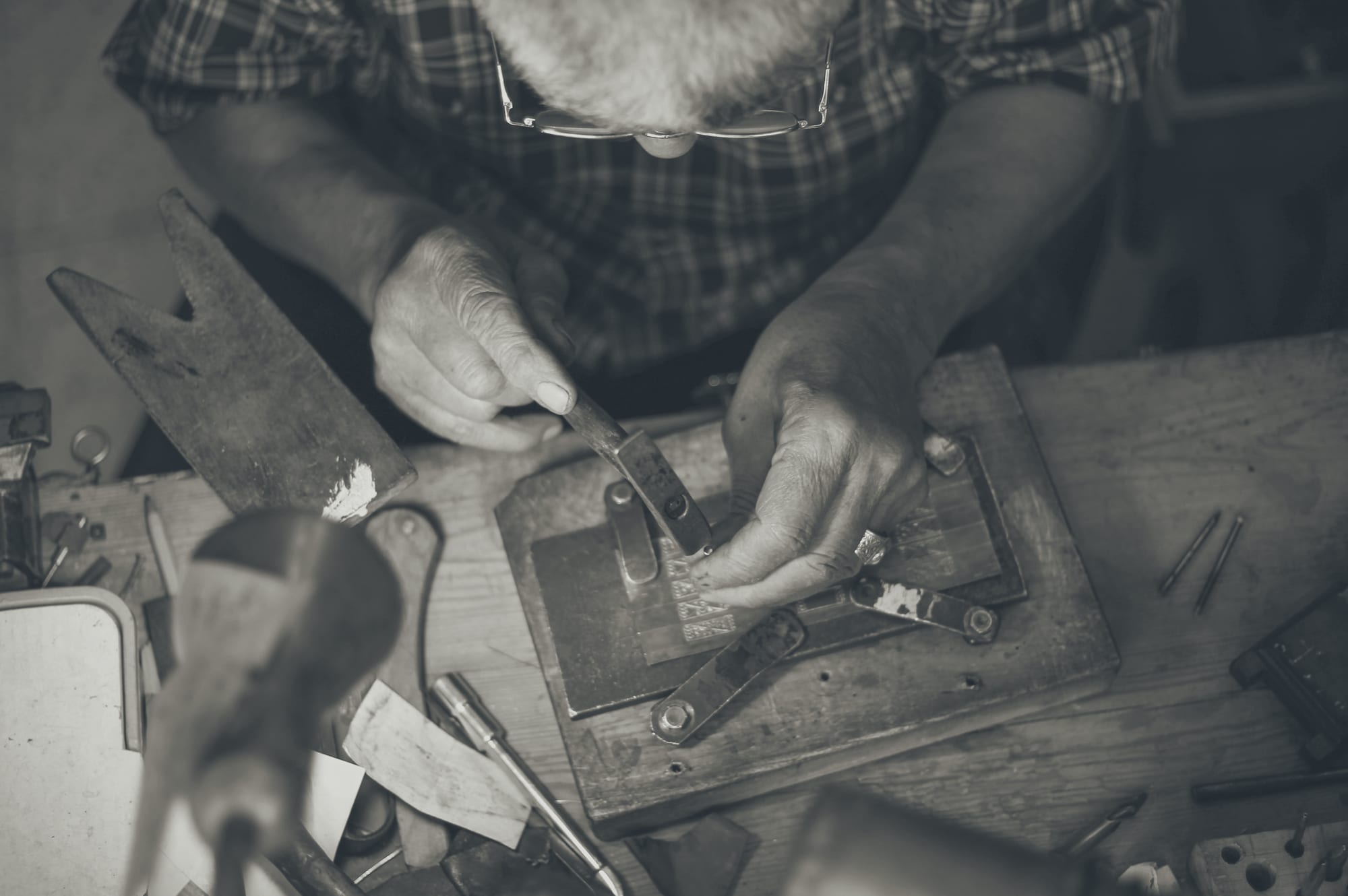 Hands filing a piece of metal at a jeweler's bench
